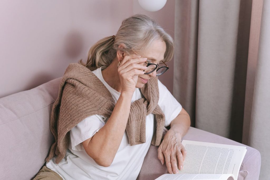 Personne âgée tenant ses lunettes en train de lire un livre